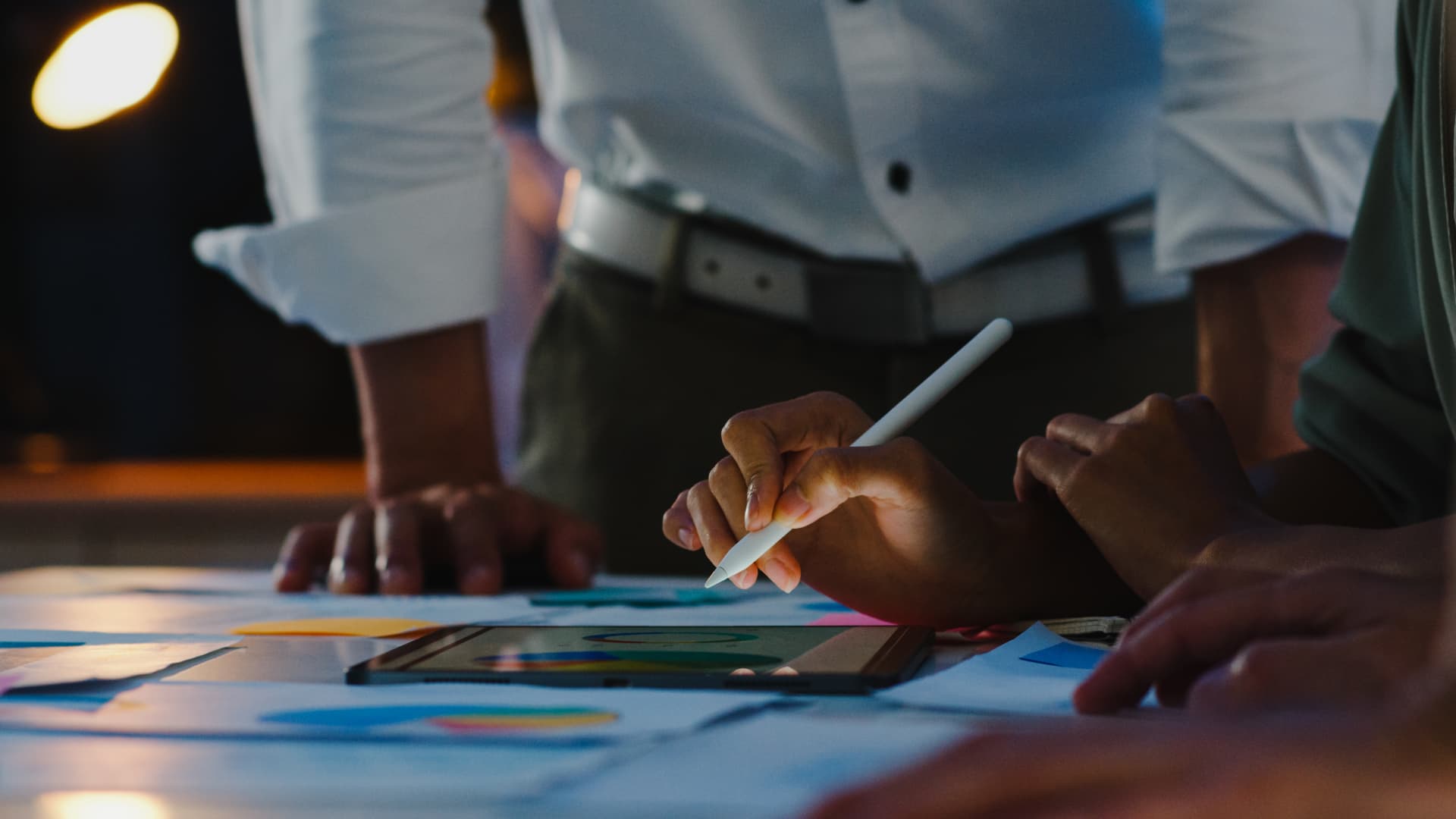 Equipe de agência trabalhando com tablet e materiais criativos sobre a mesa durante o planejamento de campanhas