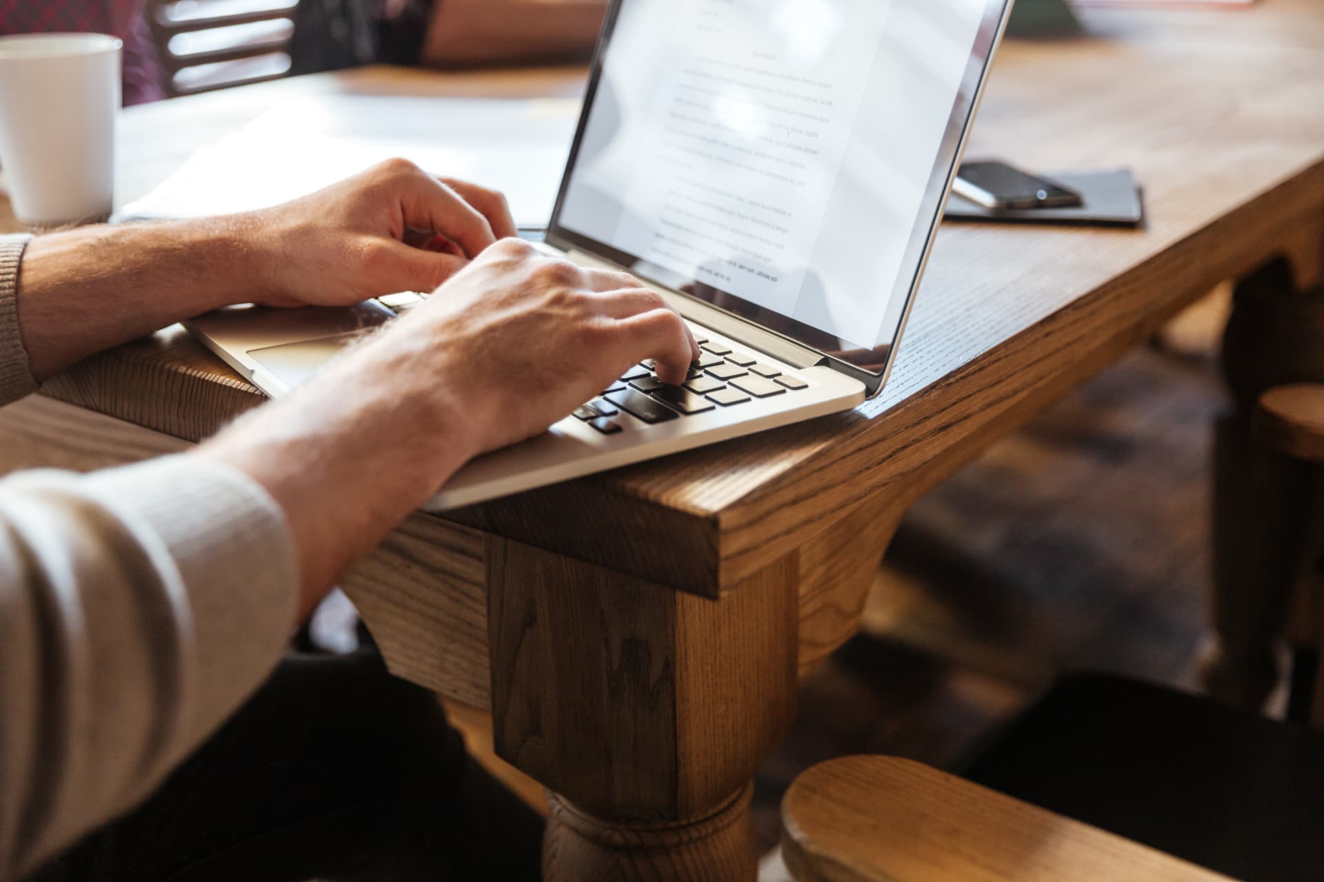 Profissional escrevendo em um notebook sobre uma mesa de madeira durante a produção de conteúdo corporativo