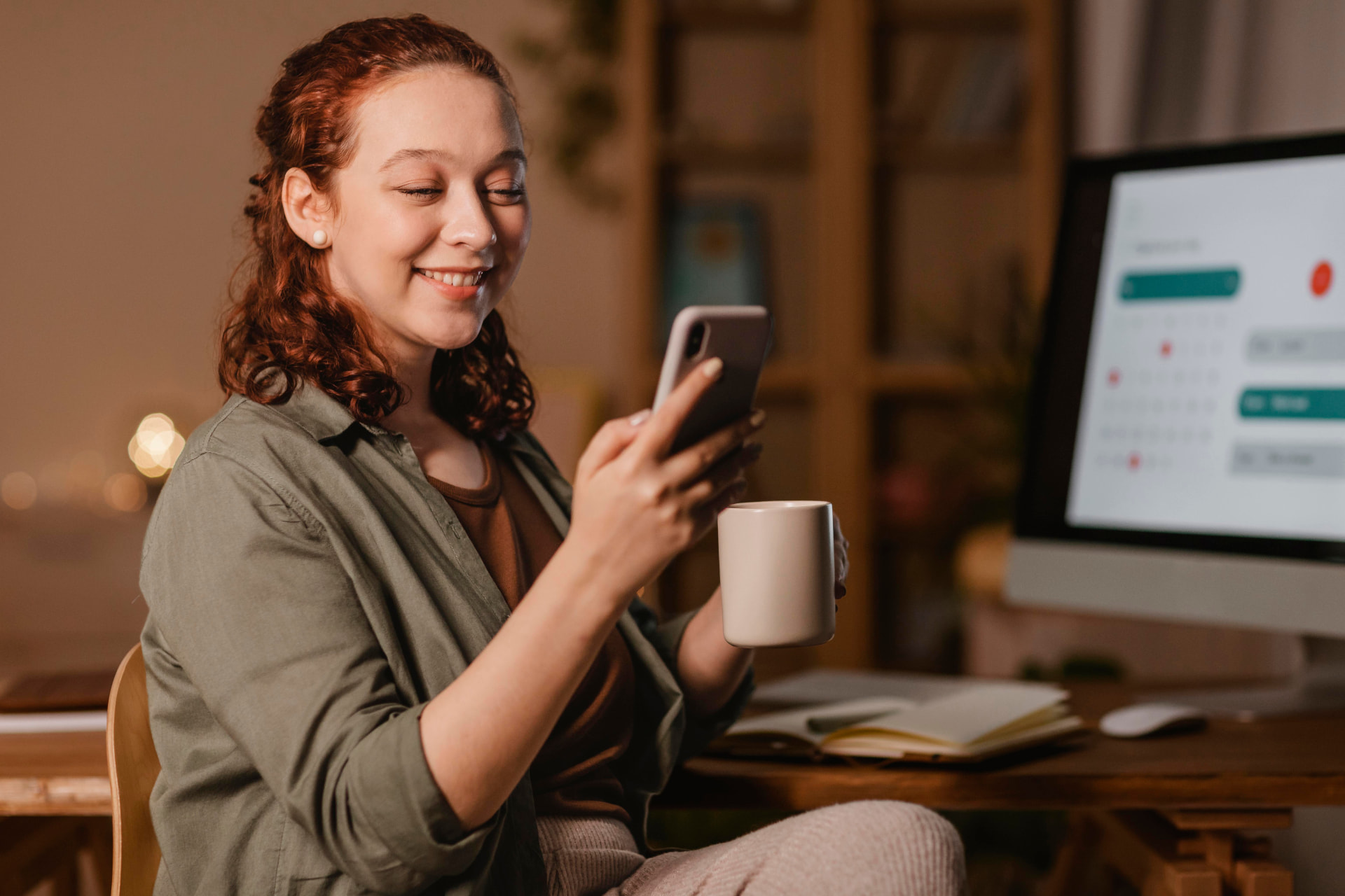 Pessoa segurando um smartphone enquanto trabalha, ilustrando o atendimento comercial pelo WhatsApp Business