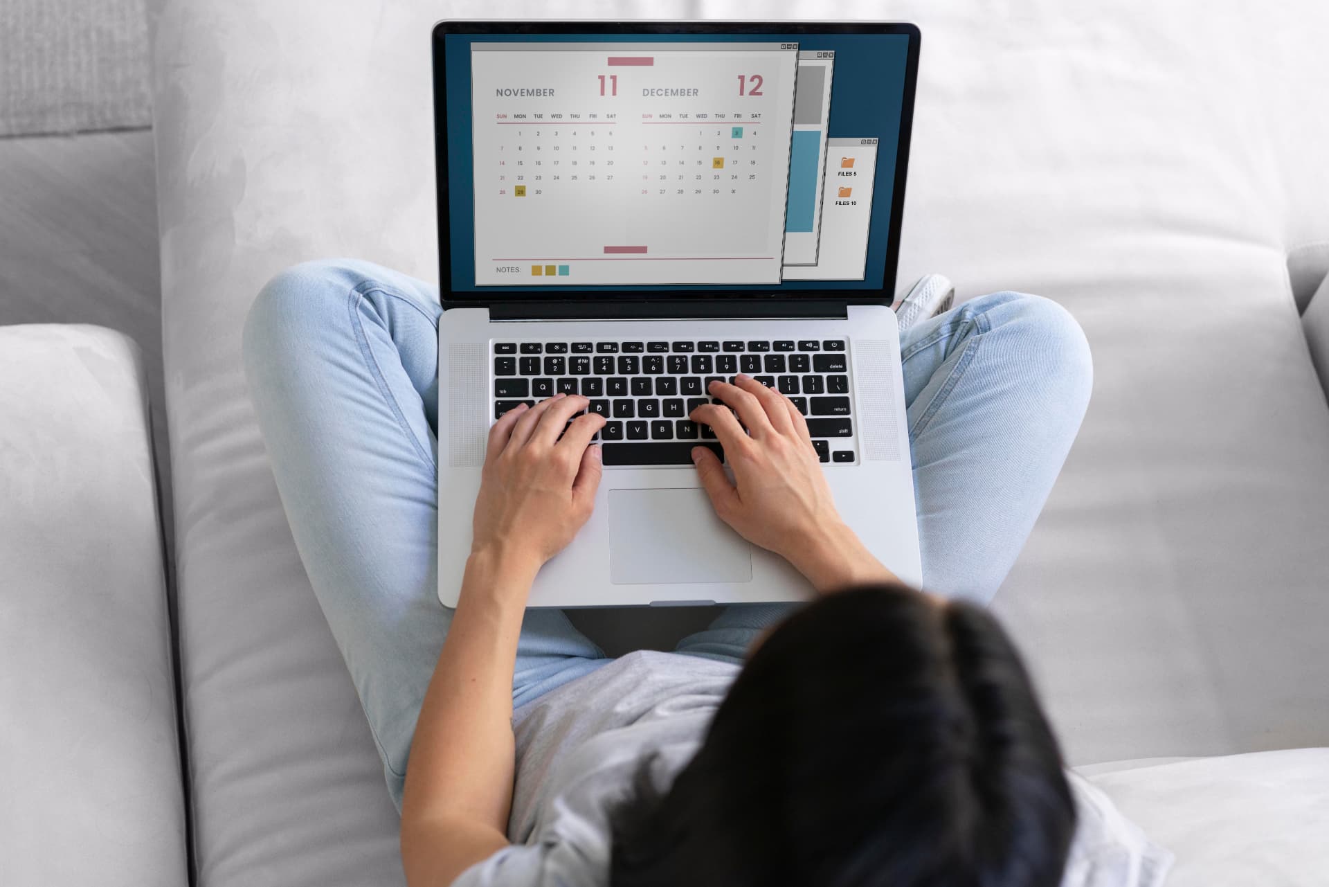 Pessoa com notebook no colo exibindo um calendário mensal na tela, ilustrando o planejamento de conteúdo para redes sociais