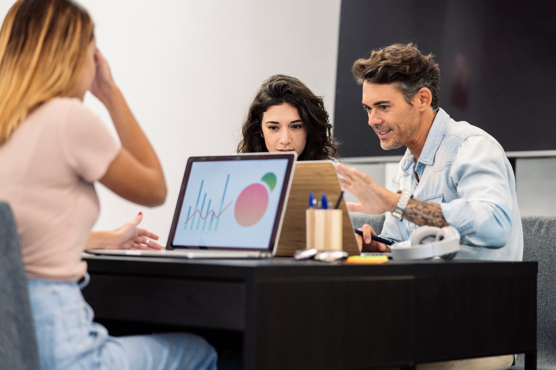 Três profissionais analisando gráficos de desempenho em um notebook durante reunião estratégica