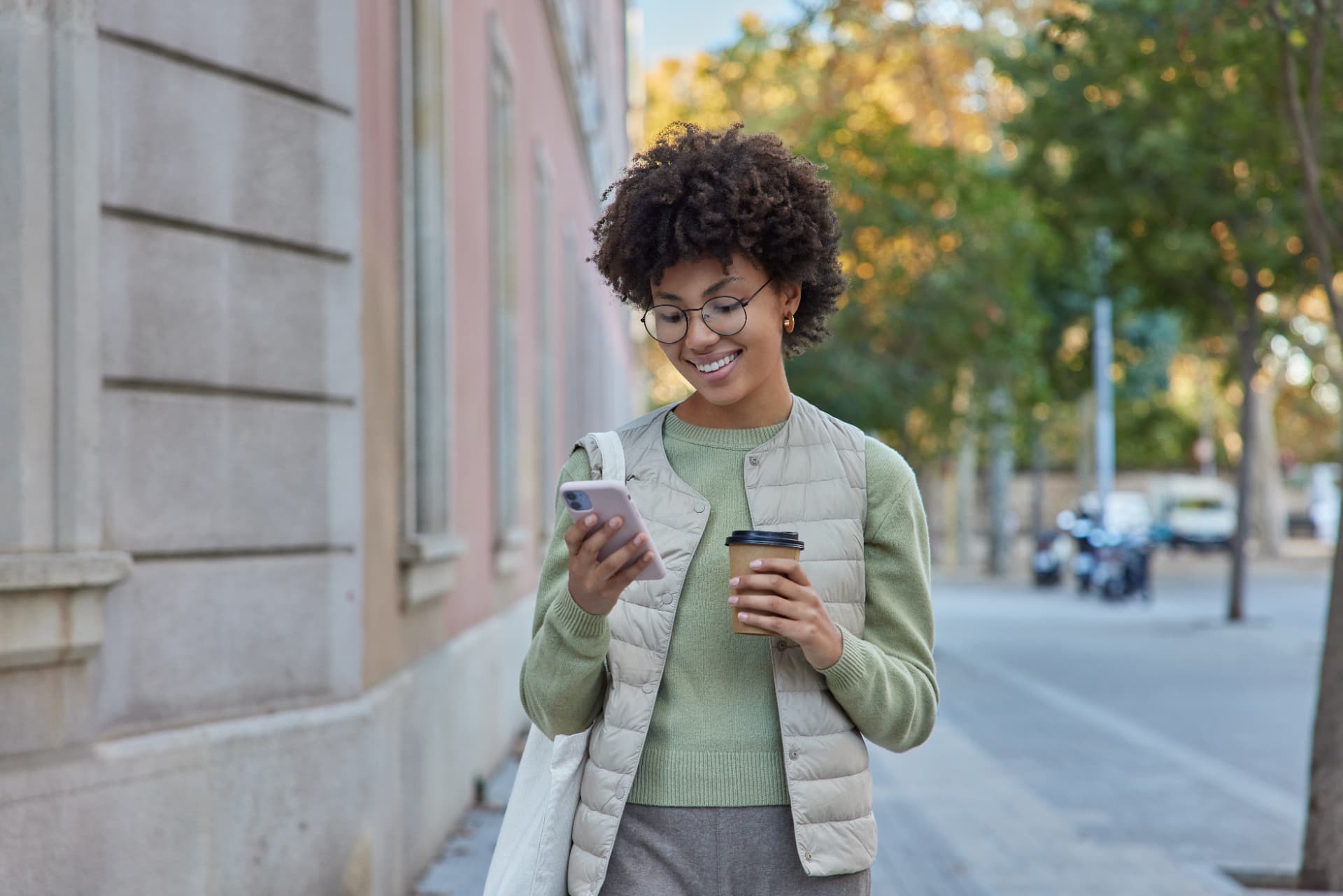 Mulher caminhando na rua sorrindo enquanto assiste vídeos curtos no celular, ilustrando a tradução por IA nos Reels