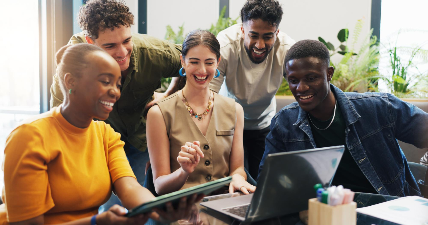 Equipe de agência de marketing comemorando resultados em frente ao notebook durante reunião de prospecção de novos clientes