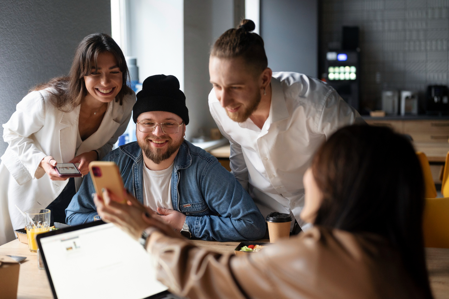 Equipe de agência reunida em volta de uma mesa no escritório conferindo posts de redes sociais em smartphones durante o planejamento do calendário editorial de conteúdo