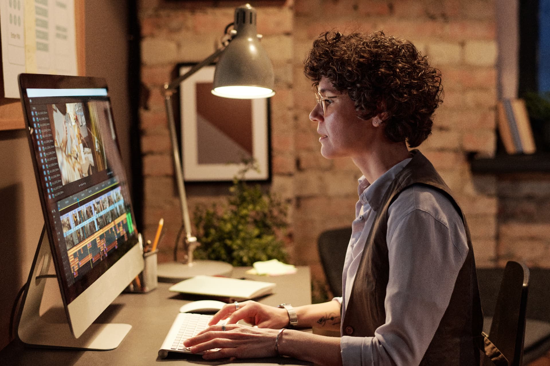 Editora de vídeo trabalhando em monitor com linha do tempo de edição, representando o cuidado com o padrão visual dos conteúdos